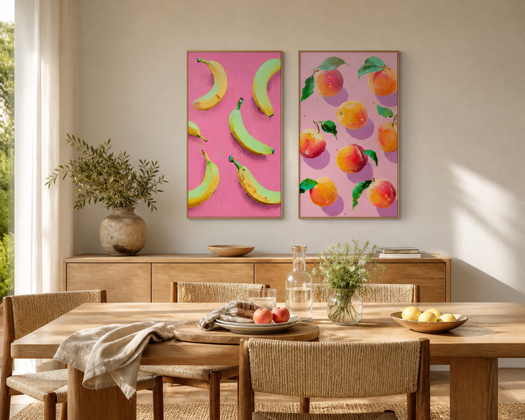 Dining room with wooden table and chairs, pink wall art of fruits, and a vase with greenery.